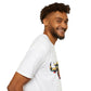 White unisex cotton t-shirt in side profile on smiling male model with curly hair and beard, featuring bold Year of the Ox graphic on chest: vibrant abstract ox/bull face portrait with large curved horns, intense eyes, geometric patterns, and dynamic multicolored paint splatters in gold, red, blue, teal, and black tones exploding outward. Chinese text "牛年" (Year of the Ox) printed below in black. Zodiac Chinese New Year motivational crewneck tee.