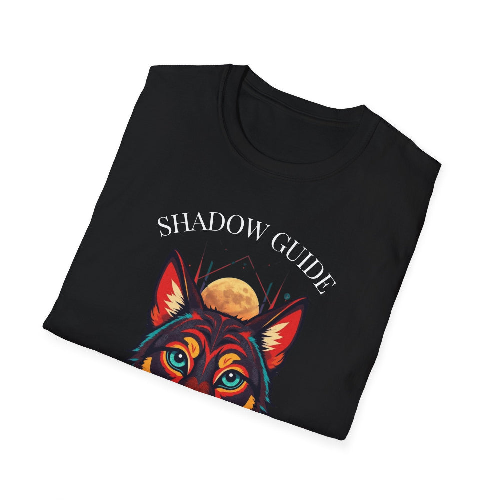 Black folded unisex cotton t-shirt featuring bold "Shadow Guide" graphic: vibrant abstract wolf head portrait with intense turquoise eyes, colorful geometric accents, and dynamic paint splatters in red, orange, teal, blue, and gold tones bursting outward around an orange moon background. Arched white text "SHADOW GUIDE" above. Motivational spiritual empowerment crewneck tee flat lay.
