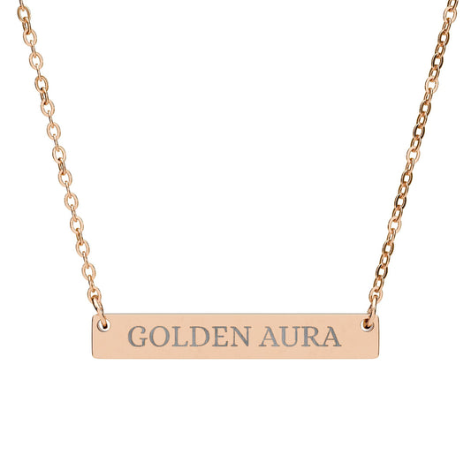 Rose gold bar necklace with engraved uppercase text "GOLDEN AURA" on a sleek matte pendant, suspended on a delicate matching rose gold chain. Minimalist motivational affirmation jewelry for radiance, positivity, and energetic glow.