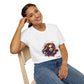 White unisex cotton t-shirt modeled by smiling woman with braided hair, hand on cheek, featuring bold "Feral" graphic: vibrant abstract portrait of a fierce woman with wild flowing hair, intense expression, tribal markings, colorful geometric accents, and dynamic paint splatters in red, orange, teal, blue, and gold tones bursting outward. White elegant cursive "Feral" text below. Wild feminine energy motivational crewneck tee.