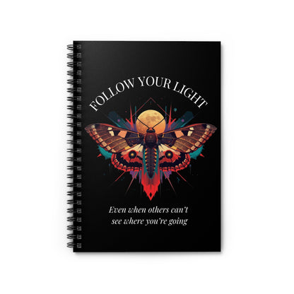 Close up of notebook with a colorful abstract moth design, intense expression, geometric accents, and paint splatters on a black background, featuring the words "FOLLOW YOUR LIGHT" and quote "Even when others can't see where you're going, see with your own eyes".