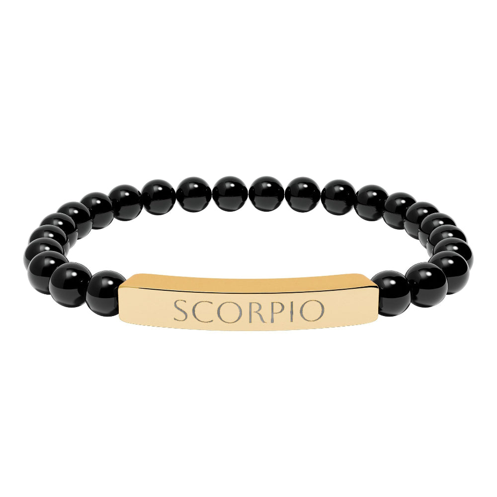 Bracelet with polished black onyx beads and gold-plated curved bar engraved "SCORPIO" in uppercase letters. Stretch-fit zodiac-inspired crystal jewelry for intensity, transformation, and emotional depth.