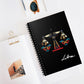 Notebook with a colorful abstract geometric scales of justice design, intricate patterns, and paint splatters on a black background, featuring the word "Libra" in elegant white cursive, placed on a clean desk with sunglasses and stationery items.