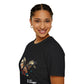 Black unisex cotton t-shirt modeled by smiling woman with braided hair, seated pose, hand on cheek, featuring bold Virgo zodiac graphic on chest: vibrant abstract woman holding wheat sheaf, serene expression, flowing hair with headscarf, detailed feathers, geometric accents, and dynamic multicolored paint splatters in gold, red, navy, teal, and black tones bursting outward. Elegant black cursive "Virgo" text below. Astrology zodiac motivational crewneck tee.