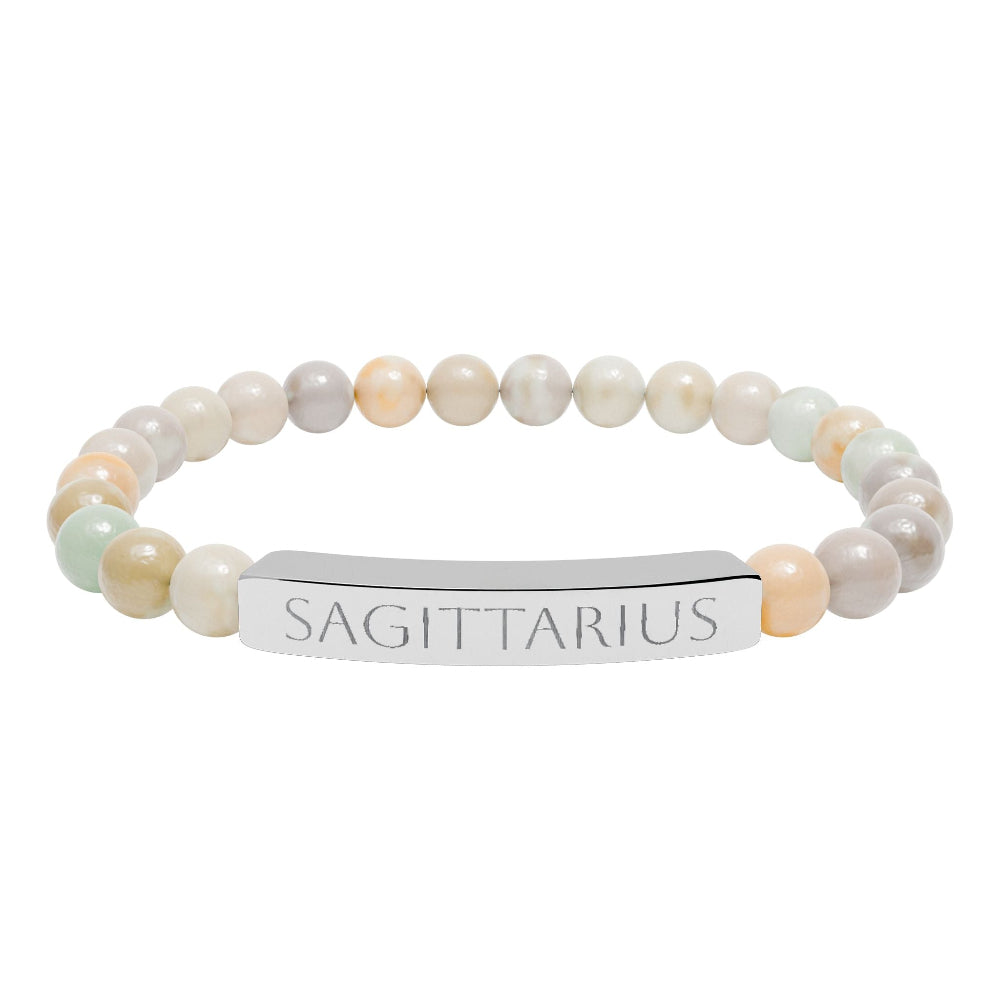 Bracelet with polished pastel beads in soft peach, cream, gray, and light blue tones with natural marbling, featuring a silver curved bar engraved "SAGITTARIUS" in uppercase letters. Stretch-fit zodiac-inspired crystal jewelry.