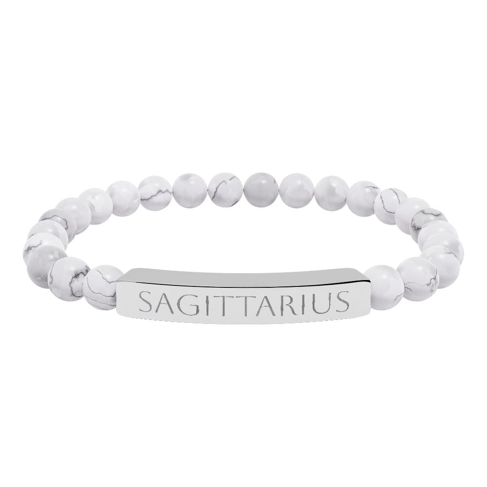 Bracelet with polished white howlite beads featuring natural gray-black veining and marbling, paired with a silver curved bar engraved "SAGITTARIUS" in uppercase letters. Stretch-fit zodiac-inspired crystal jewelry.