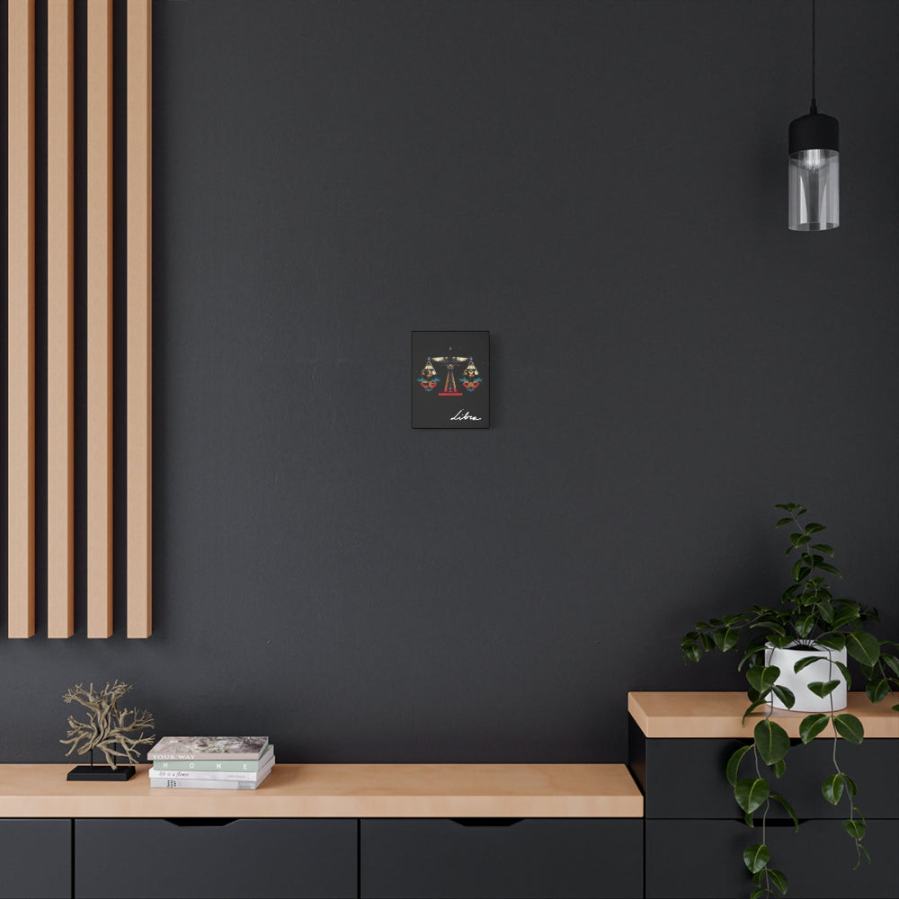 Libra zodiac canvas wall art featuring artistic balance scales illustration on black background, displayed in modern interior above wooden console with plant