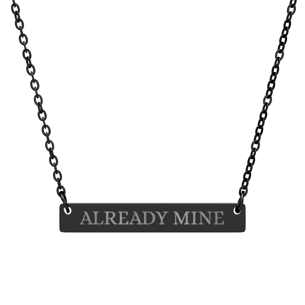 Black bar necklace with engraved uppercase text "ALREADY MINE" on a matte black pendant, suspended on a delicate black chain. Minimalist motivational affirmation jewelry for self-ownership, confidence, and empowerment.