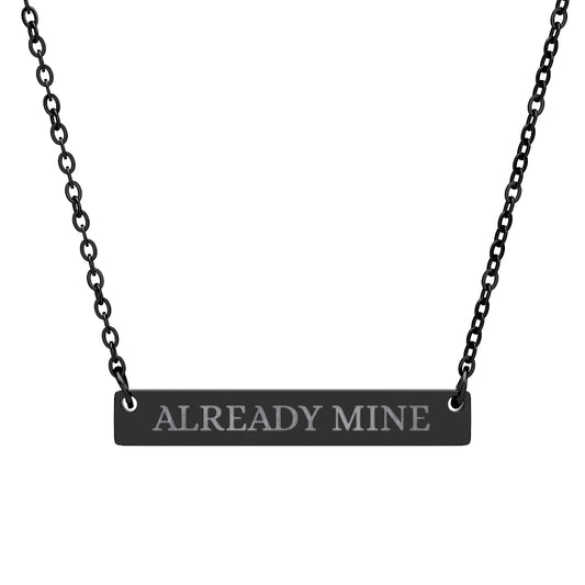 Black bar necklace with engraved uppercase text "ALREADY MINE" on a matte black pendant, suspended on a delicate black chain. Minimalist motivational affirmation jewelry for self-ownership, confidence, and empowerment.