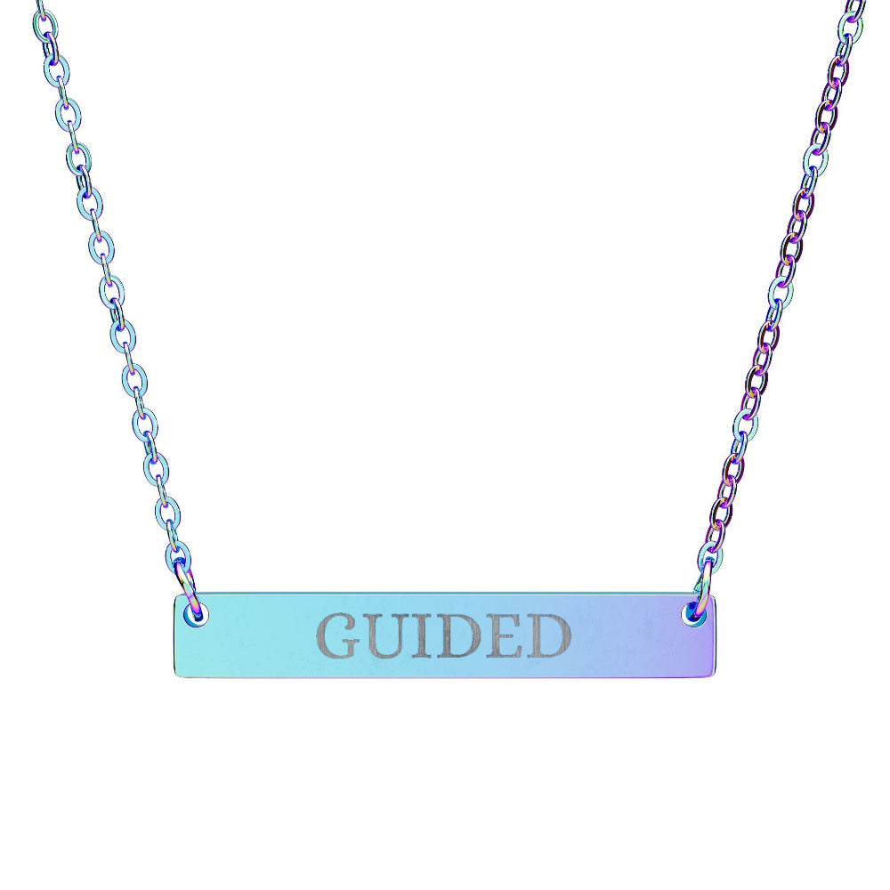 Iridescent bar necklace with engraved uppercase text "GUIDED" on a gradient light blue to purple pendant, suspended on a matching rainbow-tinted chain. Minimalist spiritual affirmation jewelry for guidance, intuition, and divine alignment.