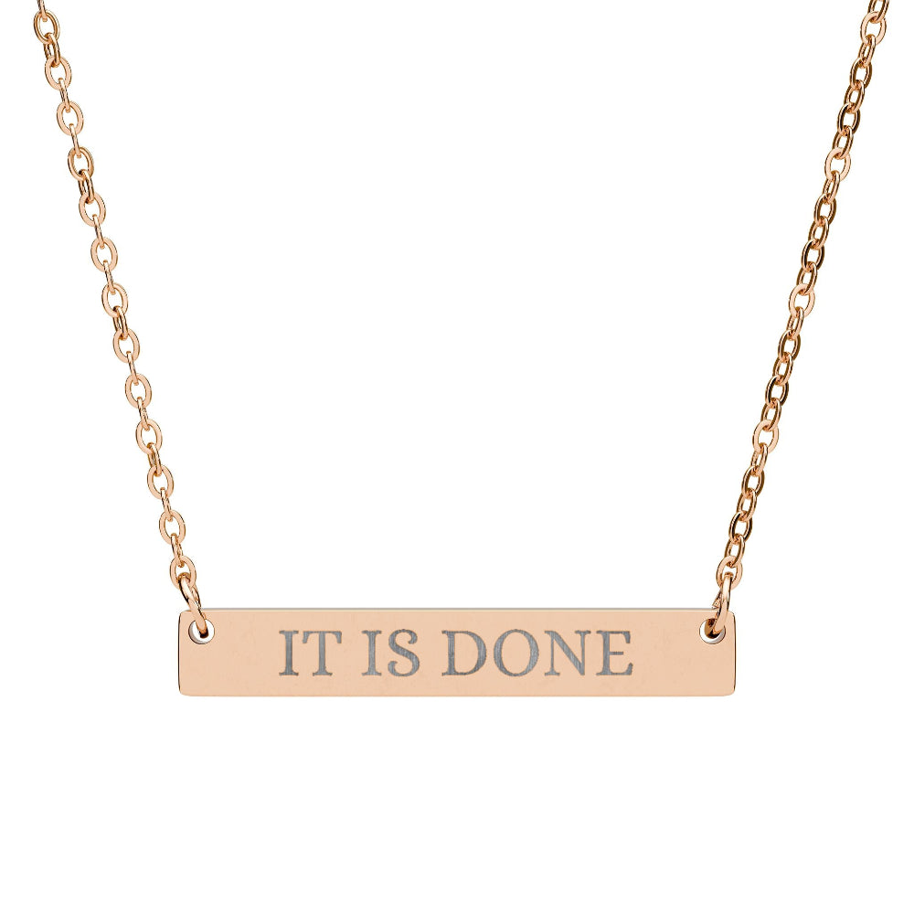 Rose gold bar necklace with engraved uppercase text "IT IS DONE" on a sleek matte pendant, suspended on a delicate matching rose gold chain. Minimalist motivational affirmation jewelry for manifestation and completion.