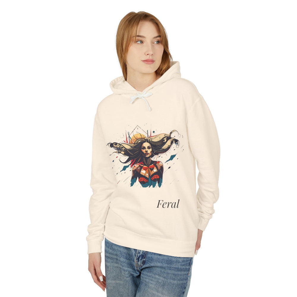 Young woman with long hair wearing cream hoodie featuring colorful artistic print of a fierce woman with flowing hair in red-orange armored top, paint splash design, "Feral" text below