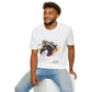 White unisex cotton t-shirt modeled by smiling man with curly hair and beard, seated pose, featuring bold Year of the Horse graphic: vibrant abstract horse head portrait with detailed mane, intense eye, bridle and harness, geometric accents, and dynamic multicolored paint splatters in gold, blue, red, black, and teal tones exploding outward. Chinese text "马年" (Year of the Horse) printed below in black. Zodiac Chinese New Year motivational crewneck tee.