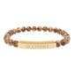 Bracelet with polished leopard jasper beads in earthy brown tones with natural veining, featuring a gold-plated curved bar engraved "SCORPIO" in uppercase letters. Stretch-fit zodiac-inspired natural stone jewelry for intensity, transformation, and emotional depth.