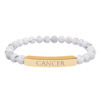 Bracelet with polished white howlite beads featuring natural gray-black veining and marbling, paired with a gold-plated curved bar engraved "CANCER" in uppercase letters. Stretch-fit zodiac-inspired crystal jewelry.