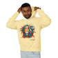 Young man with short hair pulling up the hood of a pale yellow hoodie featuring vibrant artistic portrait of a fierce woman with curly multicolored flowing hair, teal red blue face accents, bold makeup, "Feral" text below