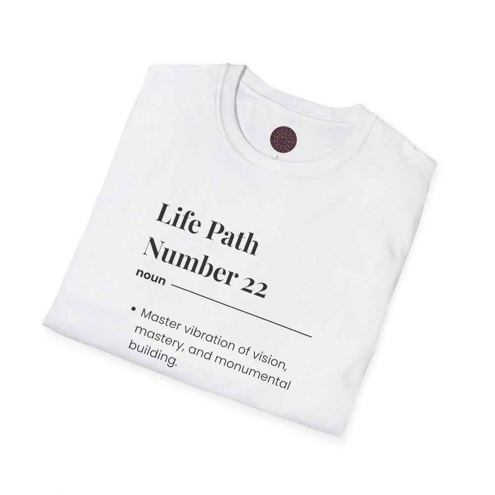 White folded unisex cotton t-shirt featuring bold Life Path Number 22 numerology print in dictionary style: exact text reading "Life Path Number 22 noun · Master vibration of vision, mastery, and monumental building." Motivational spiritual numerology crewneck tee flat lay with visible purple/gold zodiac wheel inner tag.