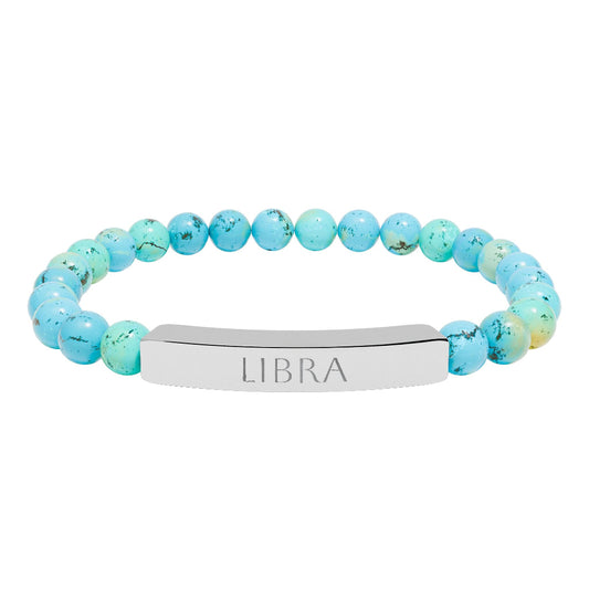 Bracelet with polished turquoise beads in soft aqua-blue tones with natural veining and speckles, featuring a silver curved bar engraved "LIBRA" in uppercase letters. Stretch-fit zodiac-inspired crystal jewelry.