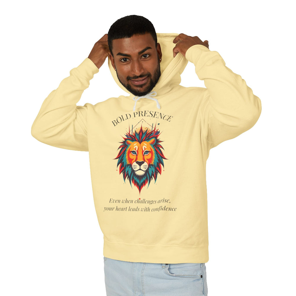 Young man with short hair pulling up the hood of a yellow hoodie featuring vibrant artistic print of a fierce woman with long flowing hair, red-orange armored top, colorful paint splash design, "Feral" text below