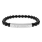 Bracelet with polished black onyx beads and silver curved bar engraved "AQUARIUS" in uppercase letters. Stretch-fit zodiac-inspired crystal jewelry.