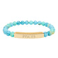 Bracelet with polished turquoise beads in soft aqua-blue tones with natural veining and speckles, featuring a gold-plated curved bar engraved "PISCES" in uppercase letters. Stretch-fit zodiac-inspired crystal jewelry.