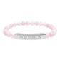 Bracelet with polished rose quartz beads in soft pink tones, natural translucent glow, paired with a silver curved bar engraved "AQUARIUS" in uppercase letters. Stretch-fit zodiac-inspired crystal jewelry.
