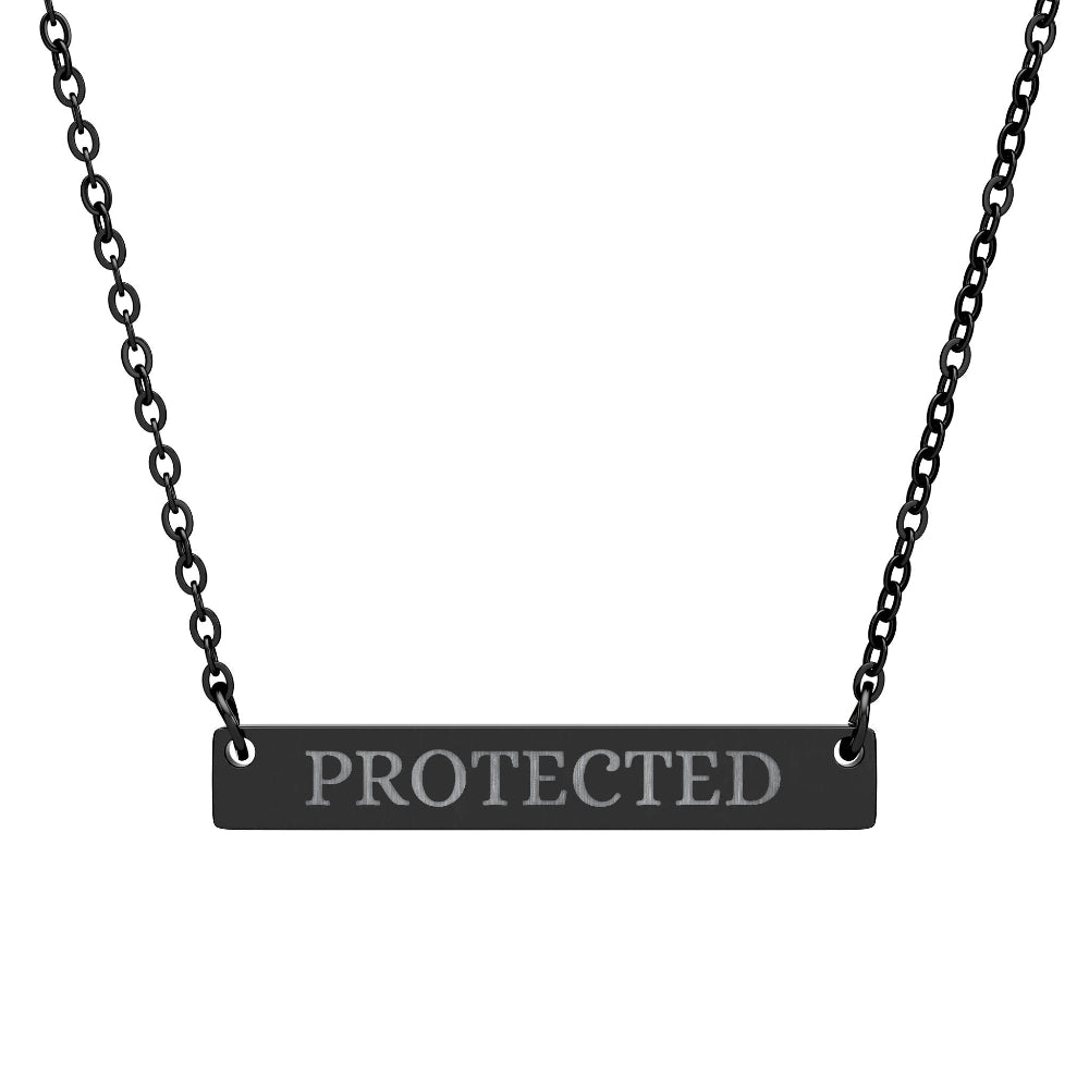 Black bar necklace with engraved uppercase text "PROTECTED" on a matte black pendant, suspended on a delicate black chain. Minimalist motivational affirmation jewelry for protection and empowerment.