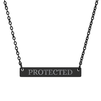 Black bar necklace with engraved uppercase text "PROTECTED" on a matte black pendant, suspended on a delicate black chain. Minimalist motivational affirmation jewelry for protection and empowerment.