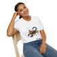 White unisex cotton t-shirt modeled by smiling woman with braided hair, seated pose, hand on cheek, featuring bold Scorpio zodiac graphic on chest: vibrant abstract scorpion silhouette with raised stinger, intense glowing eyes, detailed tail and pincers, geometric patterns, and explosive multicolored paint splatters in gold, red, navy, teal, and black tones bursting outward. Elegant black cursive "Scorpio" text below. Astrology zodiac motivational crewneck tee.