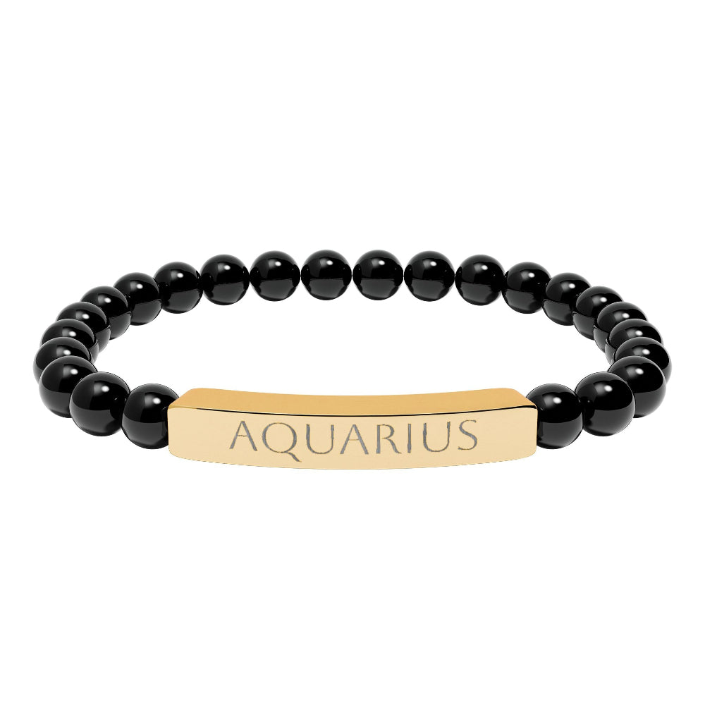 Bracelet with polished black onyx beads and gold-plated curved bar engraved "AQUARIUS" in uppercase letters. Stretch-fit zodiac-inspired crystal jewelry.