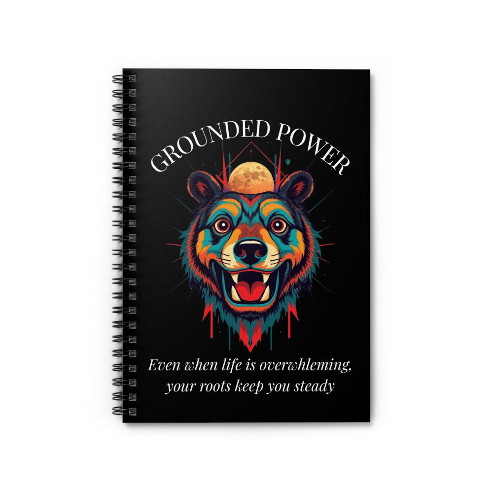 Close up of notebook with a colorful abstract bear head portrait, intense expression, flowing mane, geometric accents, and paint splatters on a black background, featuring the words "GROUNDED POWER" and quote "Even when life is overwhelming, your roots keep you steady".