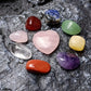 Polished crystal stones displayed in a box, including various shapes and colors, with a heart-shaped pendant and a bracelet.