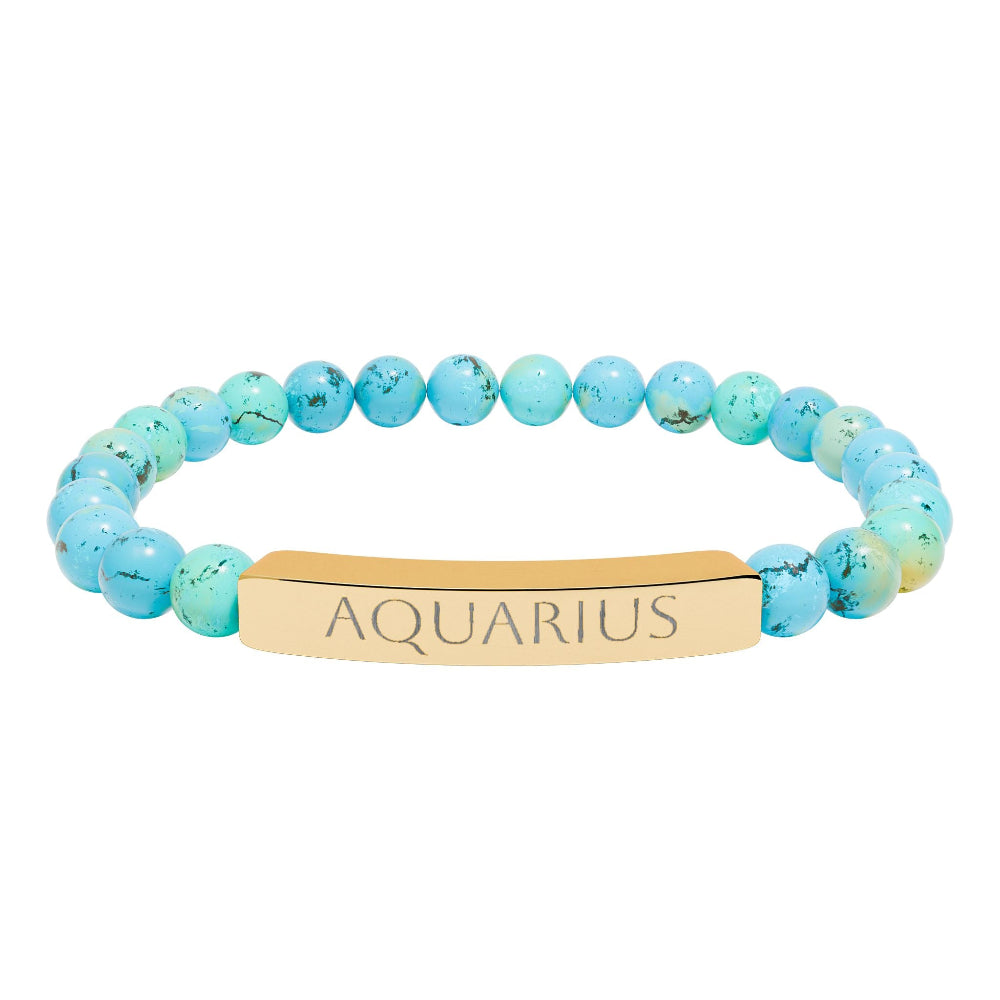 Bracelet with polished turquoise beads in soft aqua-blue tones with natural veining and speckles, featuring a gold-plated curved bar engraved "AQUARIUS" in uppercase letters. Stretch-fit zodiac-inspired crystal jewelry.
