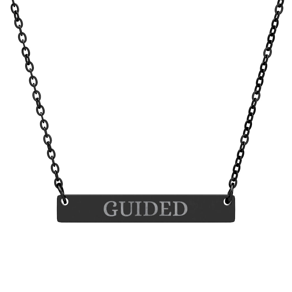 Black bar necklace with engraved uppercase text "GUIDED" on a matte black pendant, suspended on a delicate black chain. Minimalist motivational affirmation jewelry for guidance, intuition, and spiritual alignment.