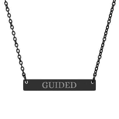 Black bar necklace with engraved uppercase text "GUIDED" on a matte black pendant, suspended on a delicate black chain. Minimalist motivational affirmation jewelry for guidance, intuition, and spiritual alignment.
