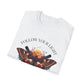 White folded unisex cotton t-shirt featuring bold "Follow Your Light" graphic: vibrant abstract moth with detailed wings, intense expression, colorful geometric accents, and dynamic paint splatters in red, orange, teal, blue, and gold tones bursting outward around an orange moon background. Arched white text "FOLLOW YOUR LIGHT" above. Motivational spiritual empowerment crewneck tee flat lay with visible purple/gold zodiac wheel inner tag.