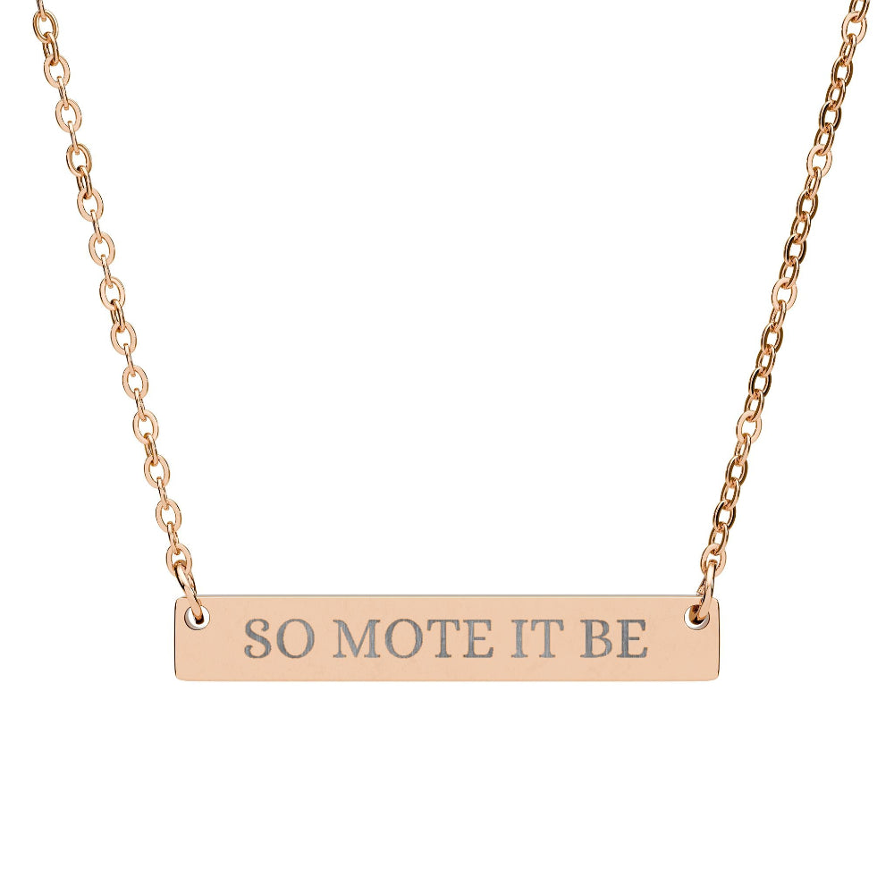 Rose gold bar necklace featuring engraved uppercase text "SO MOTE IT BE" on a sleek matte rose gold pendant, suspended on a delicate matching rose gold chain. Minimalist occult-inspired affirmation jewelry for manifestation and intention setting.