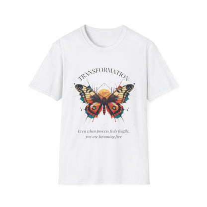 White unisex cotton t-shirt laid out flat featuring bold "Transformation" graphic: vibrant abstract butterfly with detailed wings, intense expression, colorful geometric accents, and dynamic paint splatters in red, orange, teal, blue, and gold tones bursting outward around an orange moon background. Arched white text "TRANSFORMATION" above and smaller inspirational quote "Even when process feels fragile, you are becoming free" below. Motivational spiritual empowerment crewneck tee.