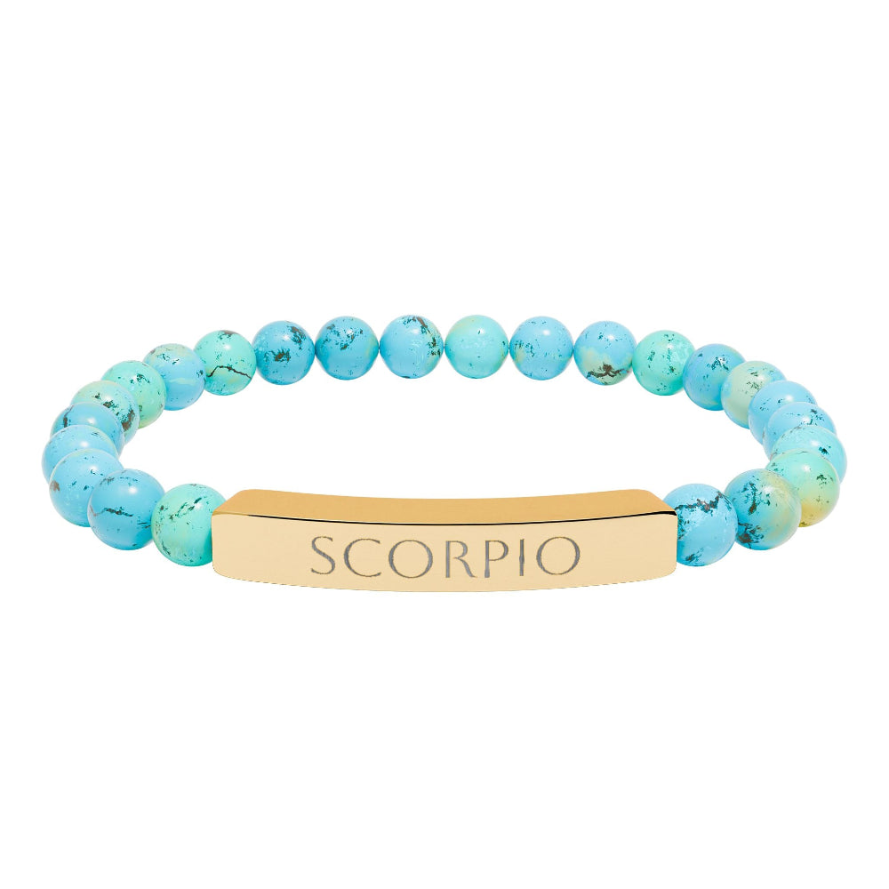Bracelet with polished turquoise beads in soft aqua-blue tones with natural veining and speckles, featuring a gold-plated curved bar engraved "SCORPIO" in uppercase letters. Stretch-fit zodiac-inspired crystal jewelry for intensity, transformation, and emotional depth.