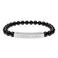 Bracelet with polished black onyx beads and silver curved bar engraved "CAPRICORN" in uppercase letters. Stretch-fit zodiac-inspired crystal jewelry.