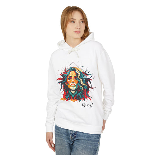 Young woman with long hair modeling white hoodie featuring vibrant artistic portrait of a fierce woman with curly multicolored flowing hair, teal red blue orange face accents, large hoop earrings, third-eye symbol, "Feral" text below
