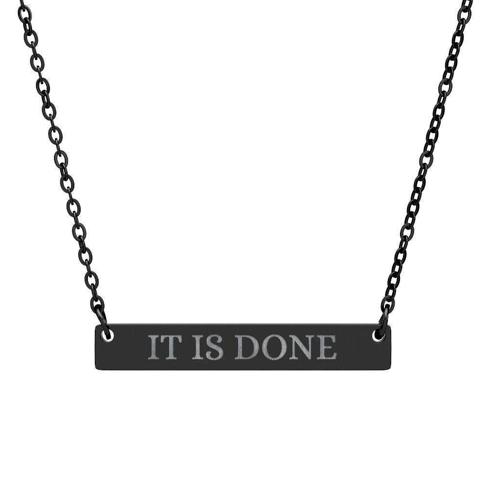 Black bar necklace with engraved uppercase text "IT IS DONE" on a matte black pendant, suspended on a delicate black chain. Minimalist motivational affirmation jewelry for manifestation and completion.