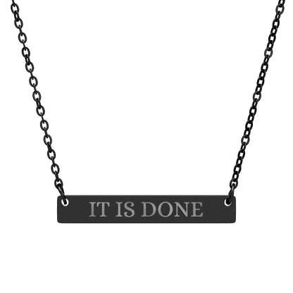 Black bar necklace with engraved uppercase text "IT IS DONE" on a matte black pendant, suspended on a delicate black chain. Minimalist motivational affirmation jewelry for manifestation and completion.