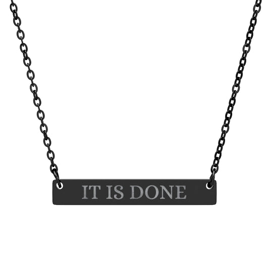 Black bar necklace with engraved uppercase text "IT IS DONE" on a matte black pendant, suspended on a delicate black chain. Minimalist motivational affirmation jewelry for manifestation and completion.