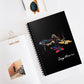 Notebook with a colorful abstract archer drawing a bow in dynamic warrior pose, flowing cape, and paint splatters on a black background, featuring the word "Sagittarius" in elegant white cursive, placed on a minimal white desk with sunglasses and stationery items.