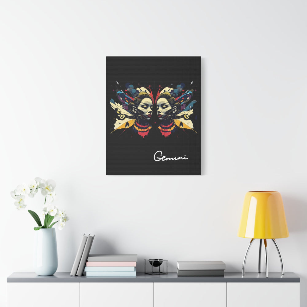 Black canvas wall art print of colorful abstract Gemini twin faces with butterfly wings and cosmic splatters on dark background, featuring "Gemini" in elegant white cursive  displayed in a modern home décor setting above a console table with books and yellow lamp.