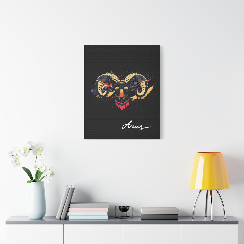 Black canvas wall art print of colorful abstract Aries ram head with curved horns, intense eyes, geometric patterns, and cosmic splatters on dark background, featuring "Aries" in elegant white cursive displayed in a modern home décor setting above a console table with books and yellow lamp.