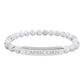 Bracelet with polished white howlite beads featuring natural gray-black veining and marbling, paired with a silver curved bar engraved "CAPRICORN" in uppercase letters. Stretch-fit zodiac-inspired crystal jewelry.