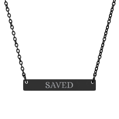Black bar necklace with engraved uppercase text "SAVED" on a matte black pendant, suspended on a delicate black chain. Minimalist motivational affirmation jewelry for grace, redemption, and spiritual protection.