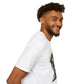 White unisex cotton t-shirt in side profile on smiling male model with curly hair and beard, featuring bold "Primal" graphic on chest: stylized intense bearded man portrait with vibrant multicolored geometric face in teal, red, orange, yellow tones, dynamic paint splatters bursting outward. Primal masculine energy motivational crewneck tee.